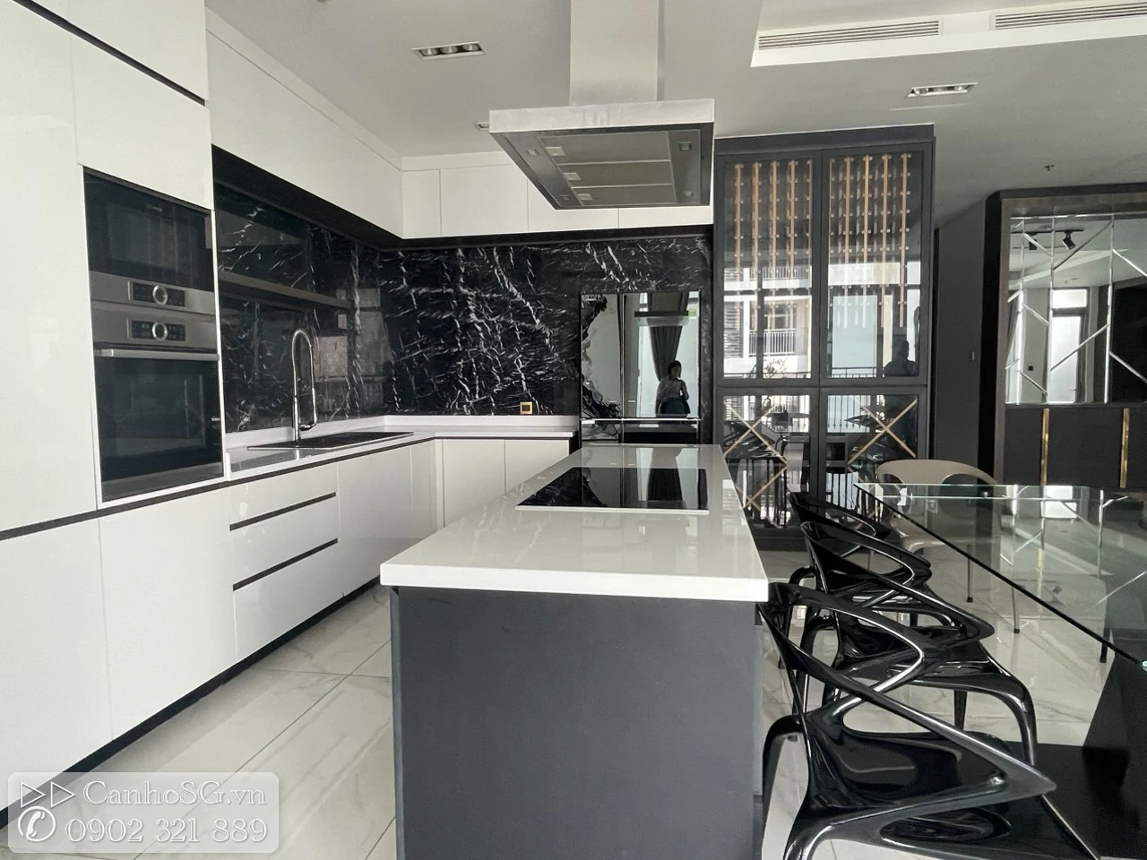 Khu bếp hiện đại với đảo bếp lớn, tủ bếp âm tường và bàn ăn kính trong căn hộ cao cấp