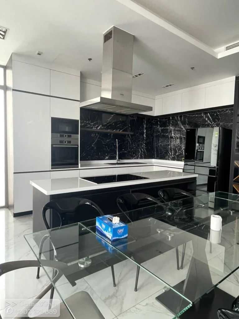 Bếp đảo trung tâm kết hợp bàn ăn kính trong căn hộ cao cấp, thiết kế hiện đại và gọn gàng