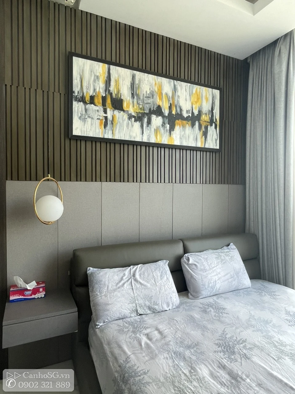 Phòng ngủ master với ốp tường gỗ, giường lớn, tranh treo tường và rèm cửa cao sát trần