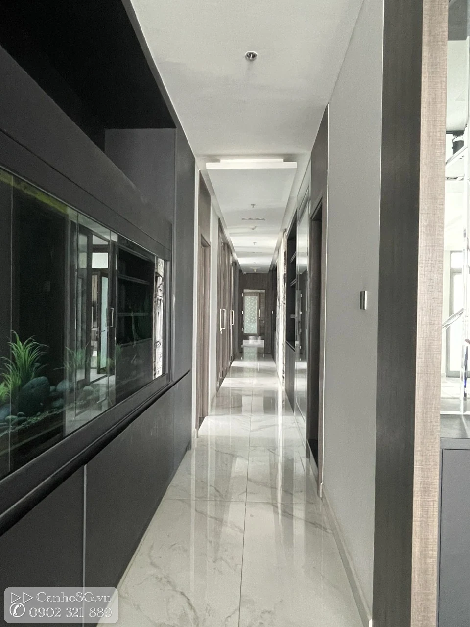Hành lang dài trong căn hộ cao cấp với sàn bóng, hệ tủ âm tường và thiết kế tối giản hiện đại