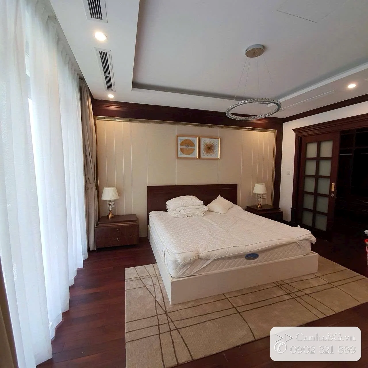 Phòng ngủ biệt thự Vinhomes River với giường đôi, rèm cửa lớn và nội thất gỗ sang trọng