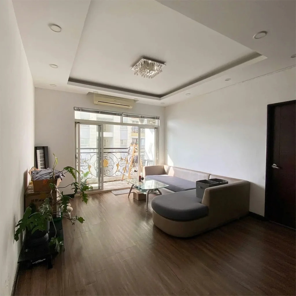 Phòng khách có sofa góc, bàn kính và cửa ra ban công tại The Flemington